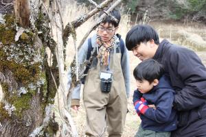 木の枝に隠れている生き物を見る親子