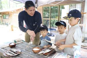 竹串にヤマメを刺す方法を教わる子どもたち