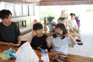 焼き上がったヤマメにかぶりつく女の子