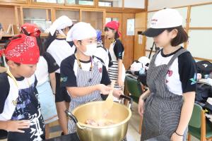 昼食作りで野菜を炒める子どもたち