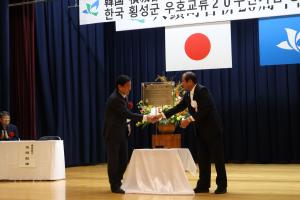 銅板の前で握手を交わす吉田町長とキム横城郡守