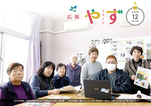 広報やず 令和7年12月号の表紙（東郡家地区まちづくり委員会での買い物支援員と利用者の集合写真）