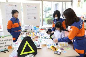 女性消防隊と一緒に非常持ち出し品を準備する子ども