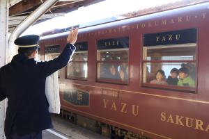 駅を守る会のメンバーが手を振って参加者を見送る様子