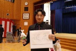 ホワイトボードに書いた抱負を掲げる田中さん