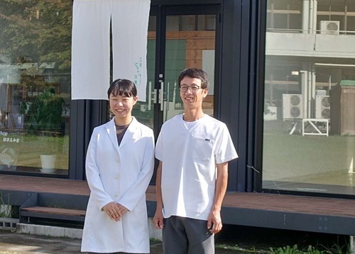 お店の前に立つ岡田夫妻の写真