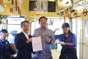 感謝状と鉄印帳マイスターカードを手に持ち、上川社長と森川さんと記念撮影をする参加者