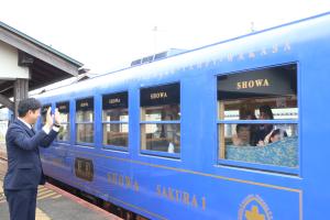 若桜鉄道観光列車「昭和号」に乗車した参加者らを見送る八頭町長