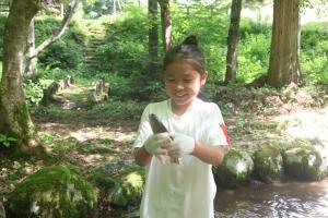 ヤマメを捕まえて笑顔をみせる子ども