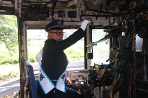 蒸気機関車の運転席に座り、汽笛を鳴らす様子