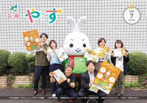 令和8年7月号の表紙（マスコットキャラクターやずぴょんと職員がデジタルポイント「やずP」のチラシやポスターを掲げている写真）