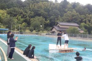 いかだの上で手押しゲームをする大学生たち
